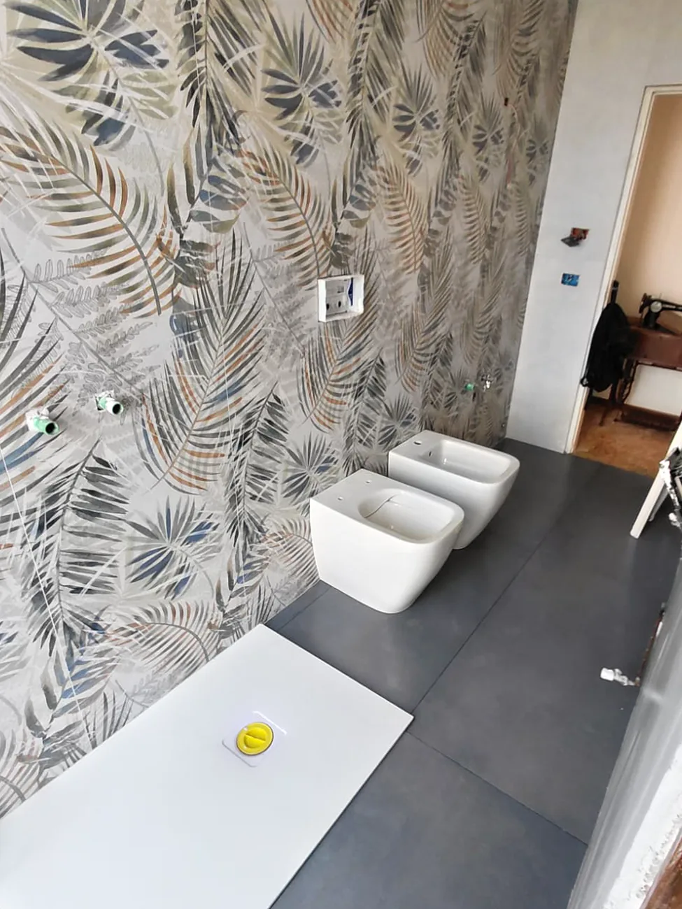 Bagno rifatto da Fasemo: parete decorata a foglie, piatto doccia filo pavimento, sanitari sospesi e pavimento in grande formato