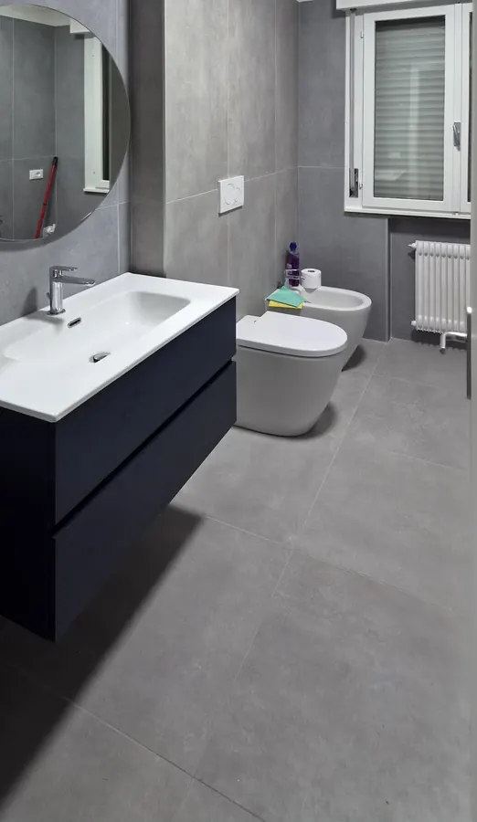 Bagno in grigio con mobile sospeso scuro e sanitari filo muro